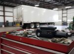 Pocket Tester trailer light tester resting on a mechanic’s toolbox inside a trailer maintenance shop